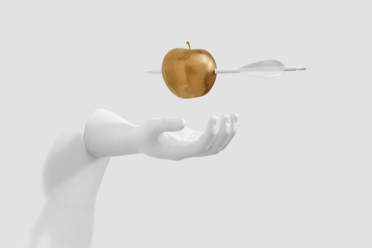 Gold Apple with Arrow Through it Floating Over White Sculpture of Outstretched Arm and Hand